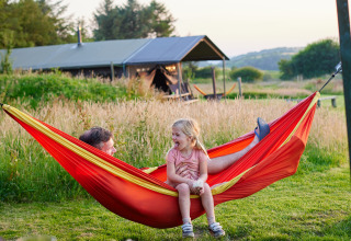 Een man en jong meisje genieten lachend samen in een hangmat bij BoerenBed Warren Farm in Zuidwest-Engeland.