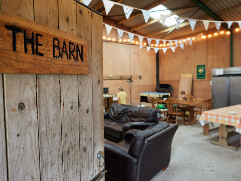 Interieur van 'The Barn' bij BoerenBed Warren Farm met banken, eettafels en vlaggetjesdecoratie.