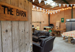 Interieur van 'The Barn' bij BoerenBed Warren Farm met banken, eettafels en vlaggetjesdecoratie.