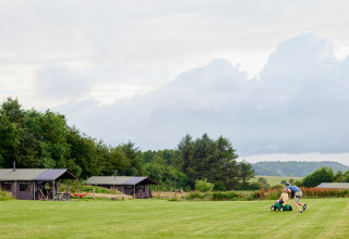 Un adulto y un niño juegan con un tractor de juguete en el césped de BoerenBed Warren Farm, suroeste de Inglaterra.