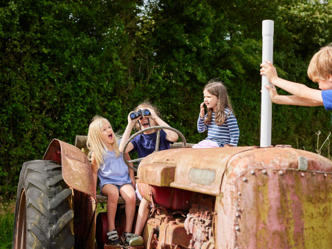 Niños juegan felices en un tractor oxidado en BoerenBed Warren Farm, en el suroeste de Inglaterra, Reino Unido.