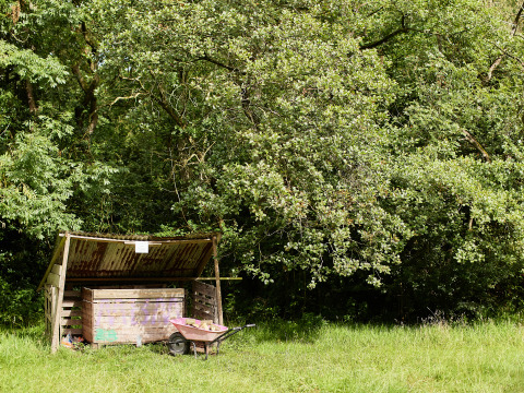 Capanno con carriola accanto ad alberi a BoerenBed Upper Shadymoor Farm, villaggio vacanze in Galles.