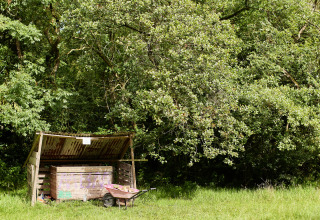 Capanno con carriola accanto ad alberi a BoerenBed Upper Shadymoor Farm, villaggio vacanze in Galles.