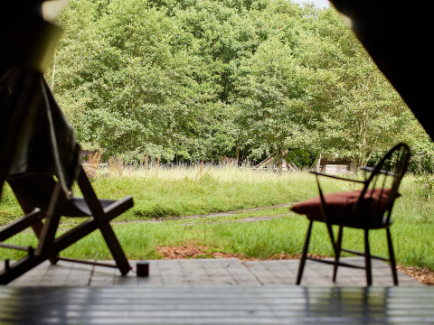 Uitzicht vanuit een tent met stoelen op het gras en bomen bij BoerenBed Upper Shadymoor Farm in Wales, VK.