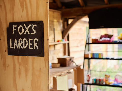 Un cartel que dice 'FOX'S LARDER' en una pared de madera en BoerenBed Upper Shadymoor Farm, Gales, Reino Unido.