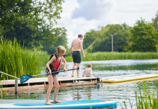 Niños y adultos disfrutan del paddle surf y se relajan junto a un lago en Upper Shadymoor Farm, Gales.
