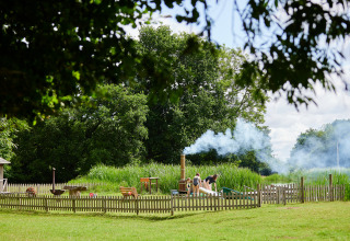 Familia disfruta al aire libre junto a un área cercada en BoerenBed Upper Shadymoor Farm, Gales, con humo.