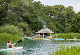 Personas practicando kayak y paddle surf en un lago junto a una cabaña en BoerenBed Upper Shadymoor Farm, Gales.