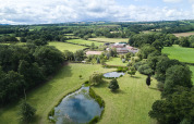 Veduta aerea di BoerenBed Upper Shadymoor Farm in Galles, UK, con stagni, campi e paesaggio verde.