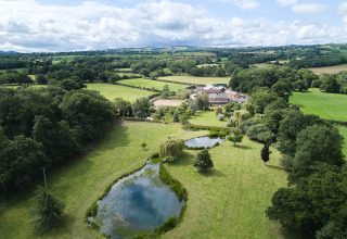 Luchtfoto van BoerenBed Upper Shadymoor Farm in Wales, VK, met vijvers, weilanden en groene natuur.