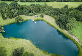Vue aérienne d’un lac paisible entouré de prairies et de forêt à BoerenBed Upper Shadymoor Farm, au Pays de Galles.