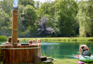 Børn i et udendørs vildmarksbad ved en sø med en mand, der gør en kajak klar på BoerenBed Upper Shadymoor Farm.