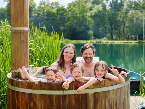 Famiglia che si rilassa in una vasca idromassaggio all’aperto al BoerenBed Upper Shadymoor Farm in Galles.