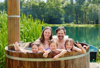 Famiglia che si rilassa in una vasca idromassaggio all’aperto al BoerenBed Upper Shadymoor Farm in Galles.