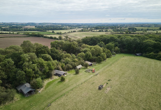 Luftfoto af BoerenBed New Barn Farm feriepark i det østlige England med telte ved skovkanten