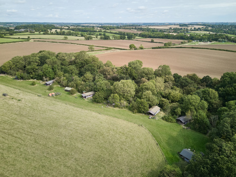 Luftfoto af BoerenBed New Barn Farm feriepark med hytter ved skovkant i det østlige England, Storbritannien.