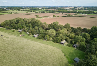 Vista aérea de BoerenBed New Barn Farm, parque vacacional con cabañas junto al bosque en el este de Inglaterra, Reino Unido.
