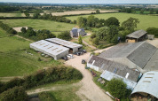 Vista aérea del parque de vacaciones BoerenBed New Barn Farm en el este de Inglaterra, con graneros y campos verdes.