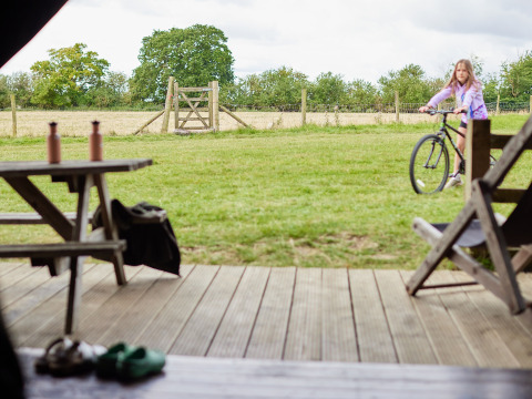 Blick aus einer Hütte im BoerenBed New Barn Farm, England, mit einem Mädchen auf einem Fahrrad.