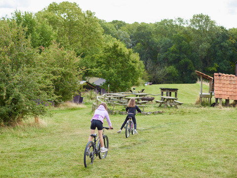 Due bambini vanno in bicicletta sull’erba al BoerenBed New Barn Farm, villaggio vacanze nell’est dell’Inghilterra.