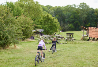 Dos niños montan en bicicleta sobre césped en BoerenBed New Barn Farm, un parque vacacional en el este de Inglaterra.