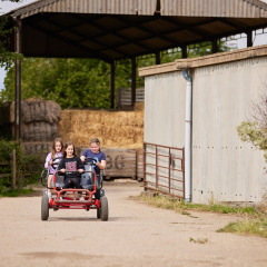 Drie kinderen op een rode skelter rijden aan een schuur bij BoerenBed New Barn Farm, Engeland.