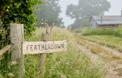 Letrero de madera que dice 'Featherdown' en un camino rural en BoerenBed Manor Farm, al sureste de Inglaterra.