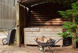 Cobertizo para leña y carretilla con madera en BoerenBed Manor Farm, en el sureste de Inglaterra.