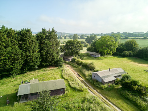 Vista aérea del parque vacacional BoerenBed Manor Farm en el sureste de Inglaterra con cabañas y campos verdes.