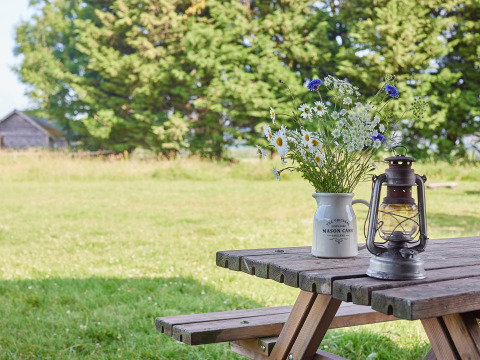Table de pique-nique en bois avec fleurs sauvages et lanterne à BoerenBed Manor Farm, Angleterre, nature.