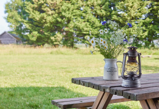 Træbord med vilde blomster i en krukke og en lanterne på BoerenBed Manor Farm, England, omgivet af natur.