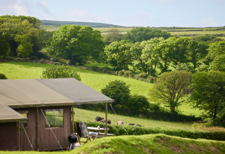 Paisaje de colinas verdes y tienda de campaña en BoerenBed Treganhoe Farm, suroeste de Inglaterra, Reino Unido.