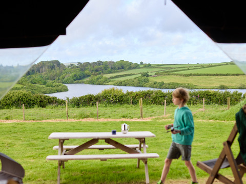 Vue champêtre à BoerenBed Treganhoe Farm, sud-ouest de l’Angleterre, avec enfant et table de pique-nique devant.