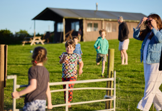 Des enfants courent et jouent sur l’herbe devant un lodge au BoerenBed Treganhoe Farm, sud-ouest de l’Angleterre.