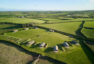 Vue aérienne du parc de vacances BoerenBed Treganhoe Farm dans le sud-ouest de l’Angleterre, entouré de champs verts.