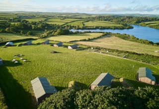 Vista aérea del parque vacacional BoerenBed Treganhoe Farm en el suroeste de Inglaterra, con campos y lago.