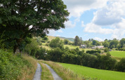 Ländlicher Weg an der BoerenBed Pant y March Farm mit Blick auf grüne Wiesen und Hügel in Wales.