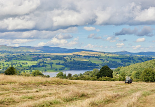 Billede af et idyllisk landskab ved BoerenBed Pant y March Farm i Wales, med grønne marker og en traktor.