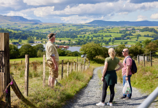 Drei Menschen unterhalten sich mit einem Einheimischen auf einem Feldweg bei BoerenBed Pant y March Farm, Wales.