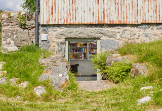 Et lille butiksvindue indbygget i en stenmur ved BoerenBed Pant y March Farm feriepark i Wales, Storbritannien.