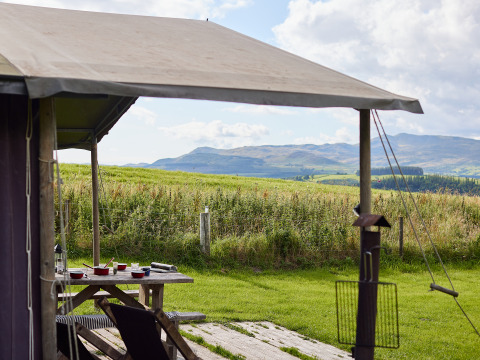 Udsigt fra BoerenBed Pant y March Farm feriepark i Wales med bord og bjerge i baggrunden.