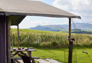 Blick vom BoerenBed Pant y March Farm Ferienpark in Wales mit Tisch und Bergen im Hintergrund.
