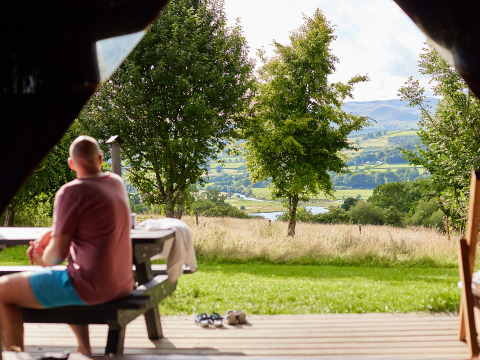 Man zit op bank met uitzicht op weilanden en heuvels bij BoerenBed Pant y March Farm in Wales, VK.