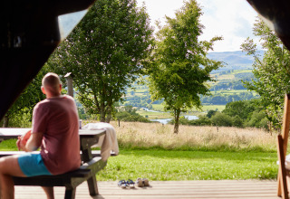 Man zit op bank met uitzicht op weilanden en heuvels bij BoerenBed Pant y March Farm in Wales, VK.