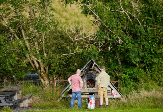To mænd forbereder et bålsted ved skovkanten på BoerenBed Pant y March Farm i Wales, Storbritannien.