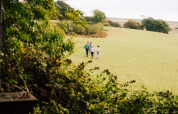 Family walking across a grassy field at BoerenBed Lunsford Farm holiday park in South East England, UK.