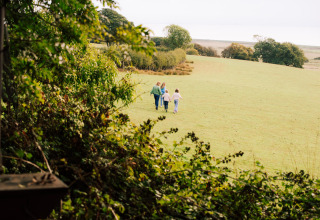 Famille marchant dans un champ à BoerenBed Lunsford Farm, parc de vacances en Angleterre du Sud-Est, Royaume-Uni.
