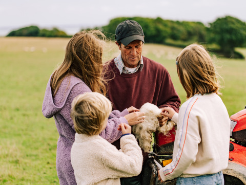 Famille découvrant la laine de mouton dans un champ à BoerenBed Lunsford Farm, parc de vacances en Angleterre du Sud-Est.