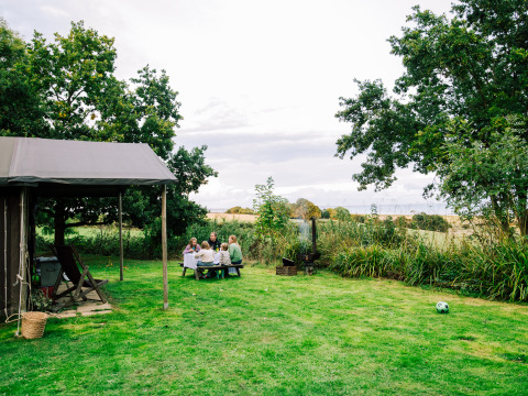 Familie nyder picnic ved bord i det grønne landskab på ferieparken BoerenBed Lunsford Farm, England.