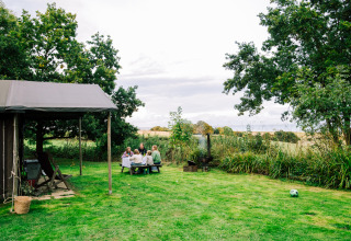 Familie nyder picnic ved bord i det grønne landskab på ferieparken BoerenBed Lunsford Farm, England.